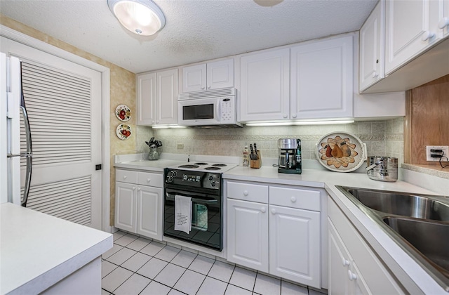 kitchen featuring backsplash, light tile floors, white cabinetry, and electric range