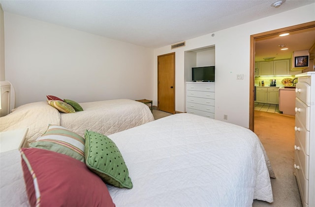 bedroom with ensuite bath and light colored carpet