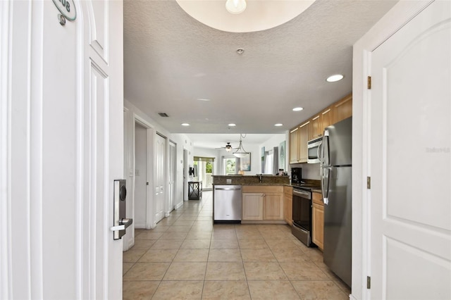 kitchen with a textured ceiling, kitchen peninsula, stainless steel appliances, and light tile flooring