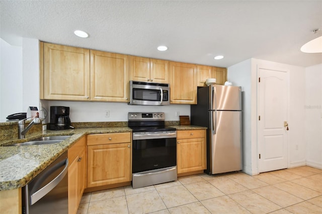 kitchen featuring appliances with stainless steel finishes, dark stone counters, light tile floors, a textured ceiling, and sink