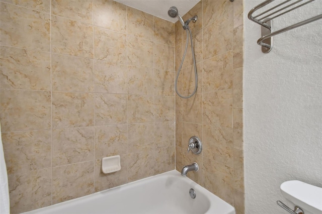 bathroom featuring tiled shower / bath and toilet