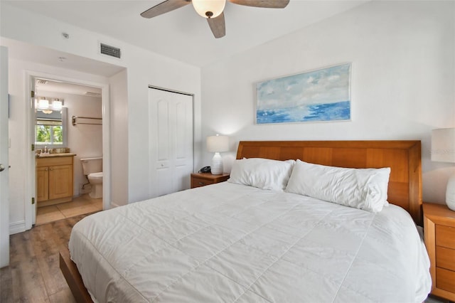 bedroom with a closet, ceiling fan, ensuite bathroom, and light hardwood / wood-style flooring