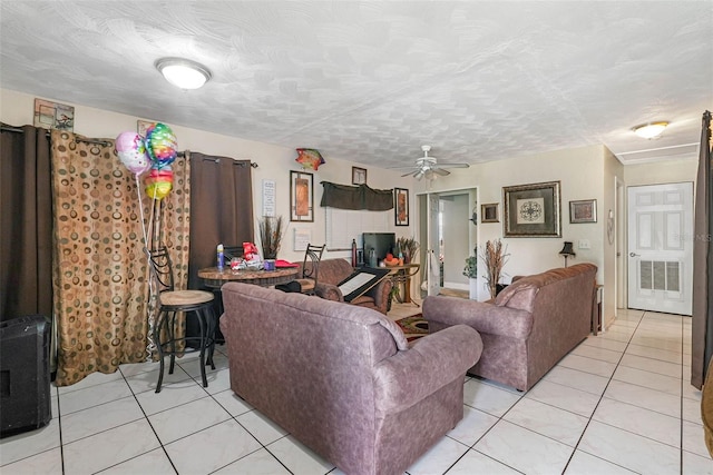 living room with ceiling fan, light tile floors, and a textured ceiling