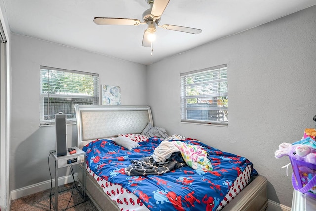 bedroom featuring dark carpet, ceiling fan, and multiple windows