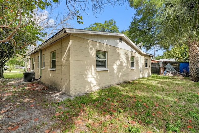 view of side of property featuring central AC unit and a lawn