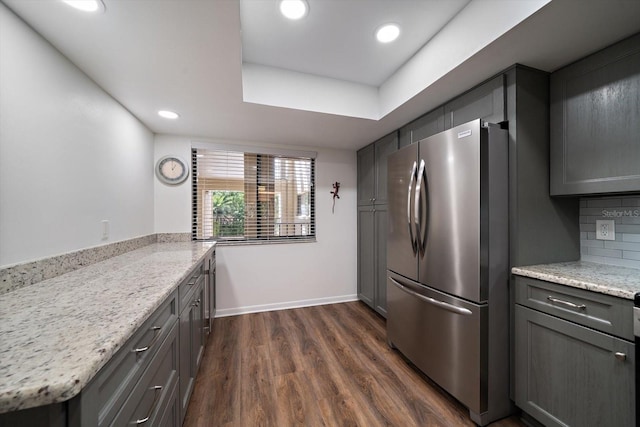 kitchen featuring stainless steel fridge, backsplash, gray cabinetry, light stone countertops, and dark hardwood / wood-style floors