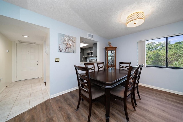 dining area with sink, light hardwood / wood-style floors, and a textured ceiling