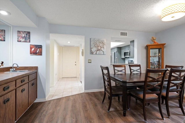 dining space featuring a textured ceiling, sink, and light wood-type flooring