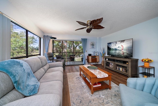 living room with ceiling fan, dark wood-type flooring, and a textured ceiling