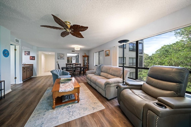 living room with ceiling fan, a textured ceiling, and dark wood-type flooring