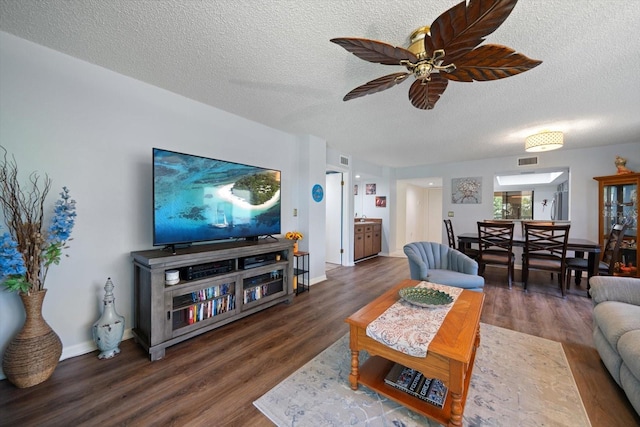 living room featuring ceiling fan, dark hardwood / wood-style floors, and a textured ceiling