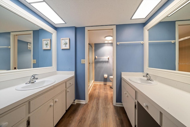 bathroom featuring hardwood / wood-style flooring, a textured ceiling, toilet, and vanity