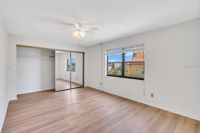 unfurnished bedroom with ceiling fan, light hardwood / wood-style flooring, and multiple windows