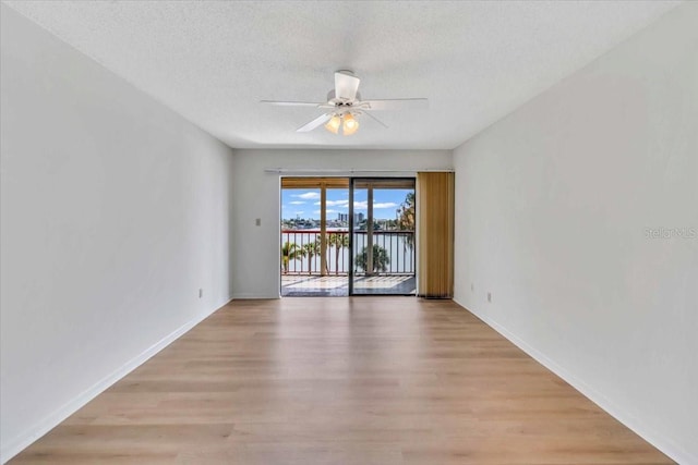 spare room with a textured ceiling, light wood-type flooring, and ceiling fan