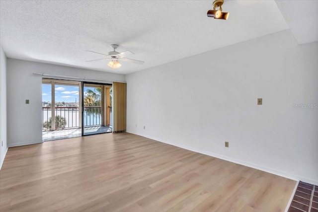 unfurnished room with ceiling fan, a textured ceiling, and light wood-type flooring