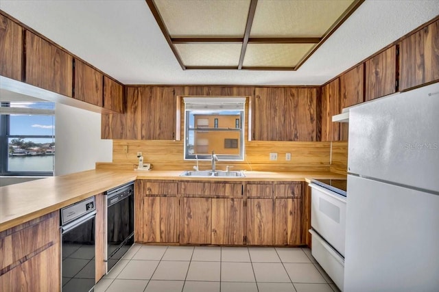 kitchen with light tile patterned flooring, a textured ceiling, white appliances, and sink