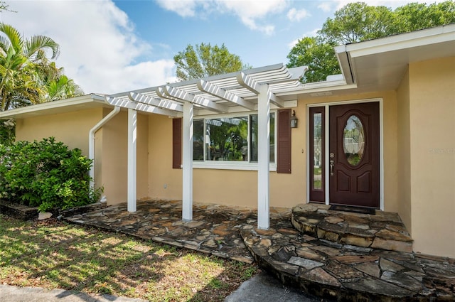 view of exterior entry featuring a pergola