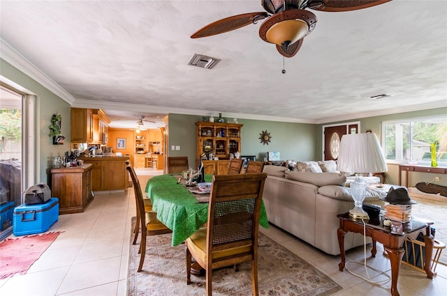 tiled dining area featuring ceiling fan and crown molding