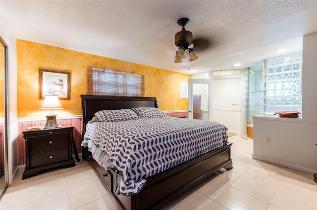 tiled bedroom featuring connected bathroom, a textured ceiling, and ceiling fan