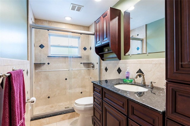 bathroom with tile walls, tile floors, toilet, and vanity with extensive cabinet space