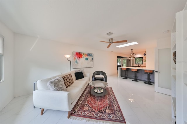 living room featuring ceiling fan and a skylight