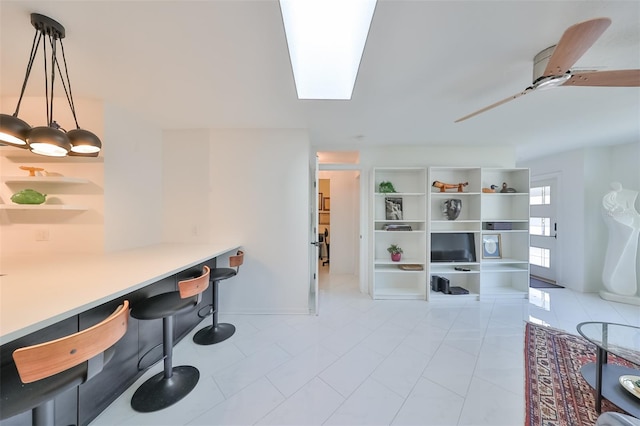 kitchen with pendant lighting, light tile patterned floors, ceiling fan, and a breakfast bar area