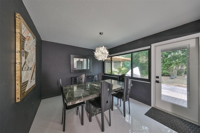 tiled dining area featuring a notable chandelier and a textured ceiling