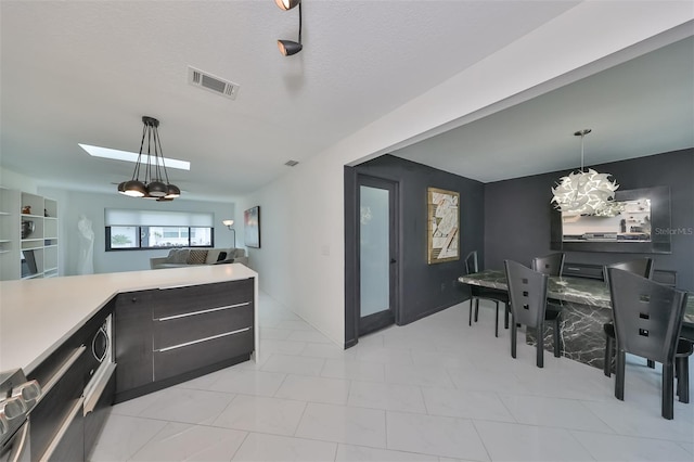 kitchen with pendant lighting, a textured ceiling, a skylight, and an inviting chandelier