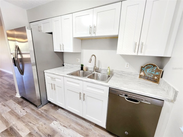 kitchen with sink, light hardwood / wood-style floors, white cabinets, and appliances with stainless steel finishes