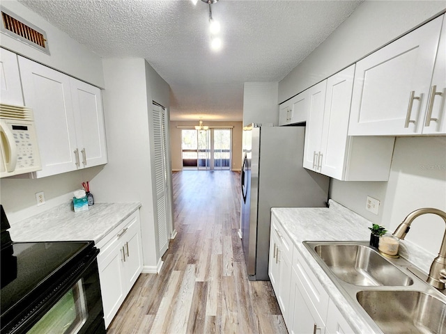 kitchen with white cabinetry, sink, light wood-type flooring, a textured ceiling, and black / electric stove