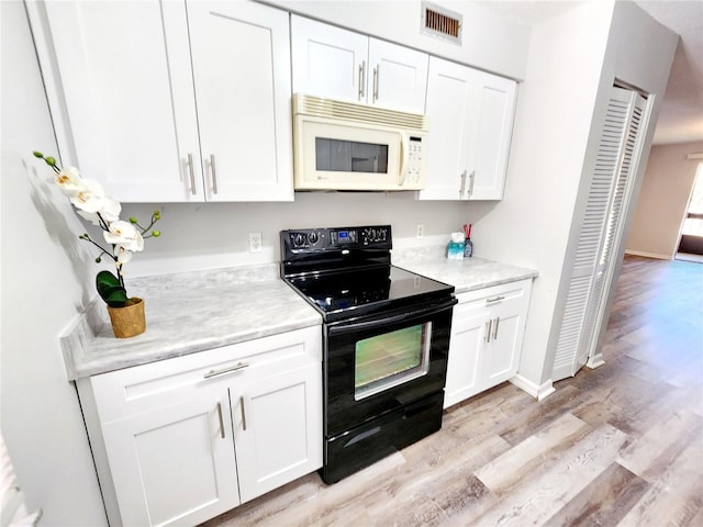 kitchen with white cabinets, light wood-type flooring, and electric range