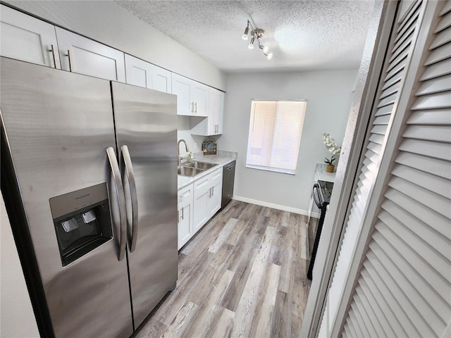 kitchen featuring appliances with stainless steel finishes, sink, a textured ceiling, and white cabinets