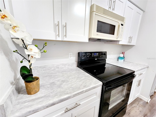 kitchen featuring black electric range, white cabinets, and light hardwood / wood-style floors