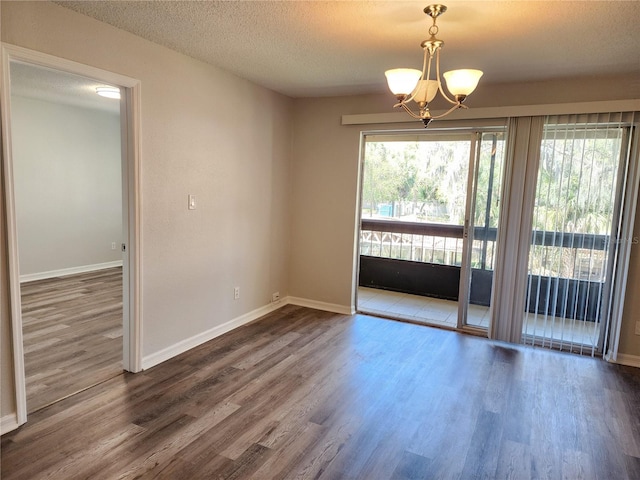 spare room with hardwood / wood-style floors, a notable chandelier, and a textured ceiling