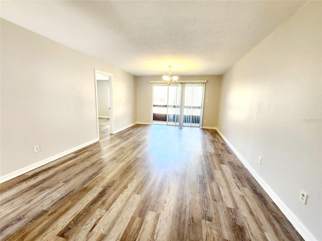 unfurnished room with hardwood / wood-style flooring, a textured ceiling, and a chandelier