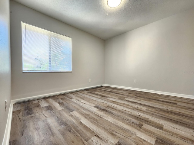 unfurnished room featuring hardwood / wood-style flooring and a textured ceiling