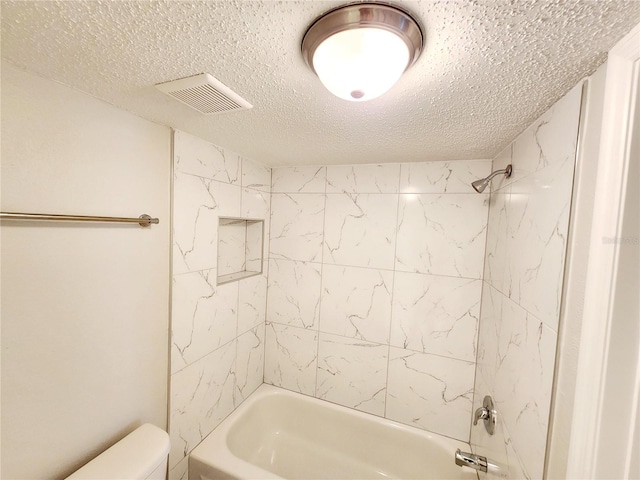 bathroom featuring tiled shower / bath combo, a textured ceiling, and toilet