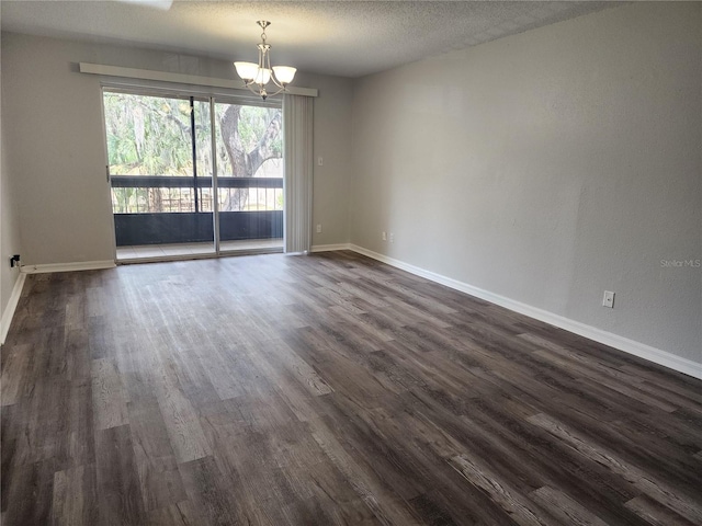 empty room featuring dark hardwood / wood-style flooring, a notable chandelier, and a textured ceiling