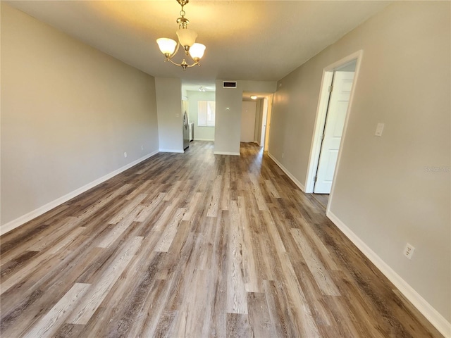 empty room with an inviting chandelier and wood-type flooring