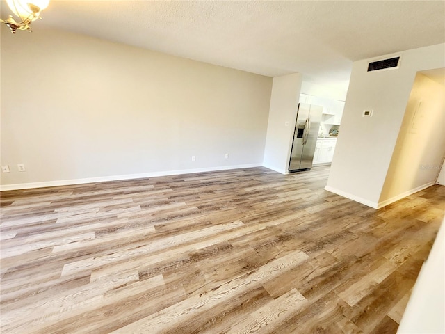 unfurnished living room featuring light hardwood / wood-style floors and a textured ceiling