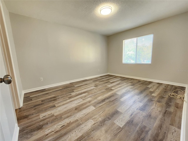 empty room with hardwood / wood-style floors and a textured ceiling