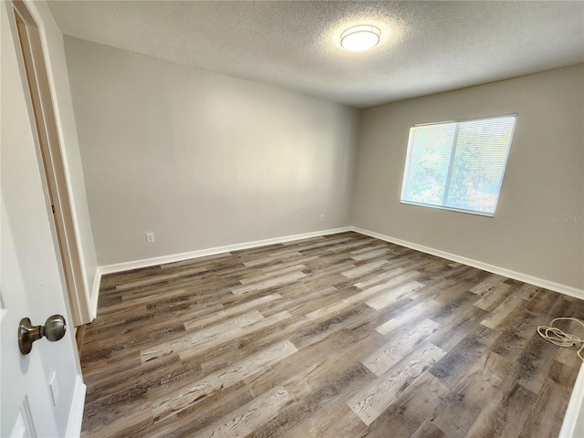 empty room with hardwood / wood-style floors and a textured ceiling