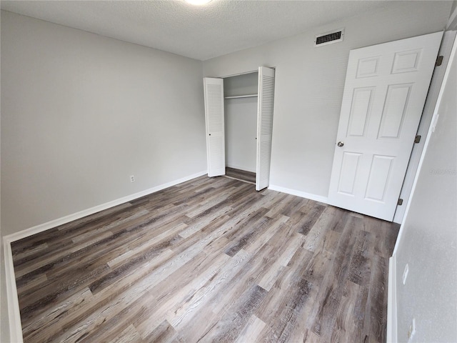 unfurnished bedroom featuring hardwood / wood-style flooring, a closet, and a textured ceiling