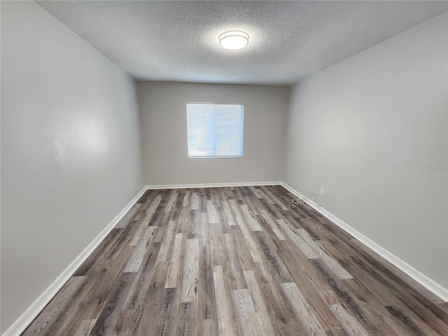 empty room with hardwood / wood-style flooring and a textured ceiling