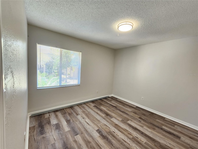 unfurnished room featuring wood-type flooring and a textured ceiling