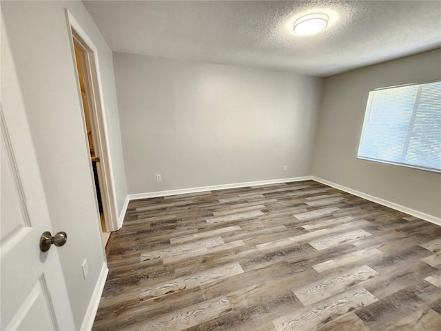 empty room with hardwood / wood-style flooring and a textured ceiling