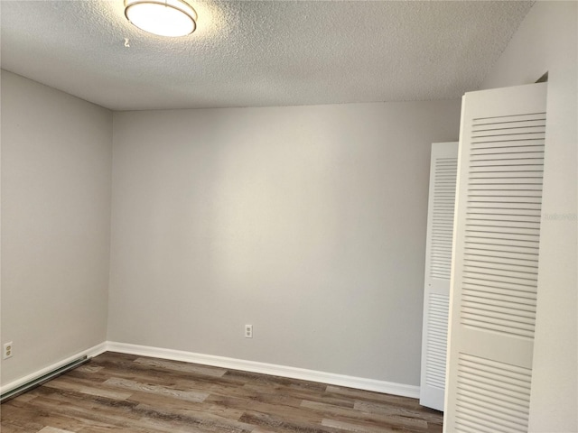 interior space featuring dark wood-type flooring, a textured ceiling, and a closet