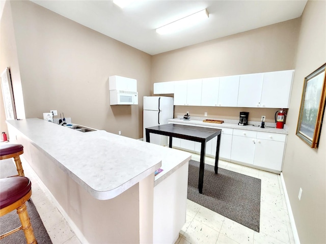 kitchen featuring white cabinetry, white appliances, a kitchen bar, and sink