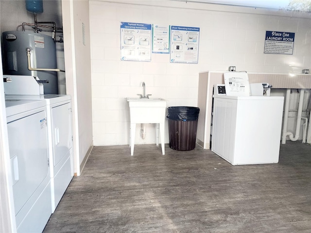 clothes washing area featuring dark wood-type flooring, washing machine and dryer, and electric water heater