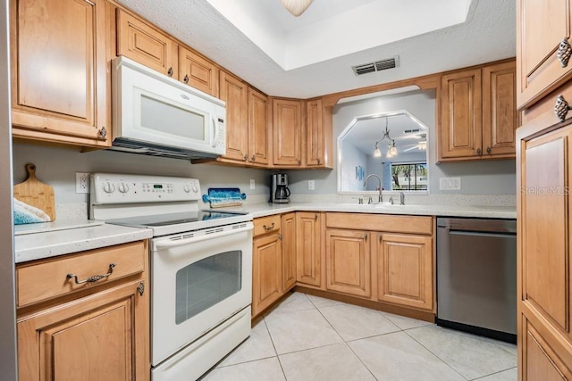 kitchen with sink, light tile floors, and white appliances